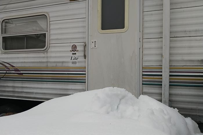 高島市でトレーラーハウスの鍵開け作業。ドアの前に雪の山を椅子代わりに作業を進めました。